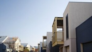 A modern urban street with contemporary buildings, including a two-story structure with a balcony and a garage door. - Harbourside Terraces (Wickham)