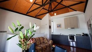 A modern living room with a wooden ceiling, a sofa, a dining area, and a kitchen. - Harbourside Terraces (Wickham)