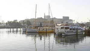 A marina with several boats docked, a clear sky, and buildings in the background. - Harbourside Terraces (Wickham)