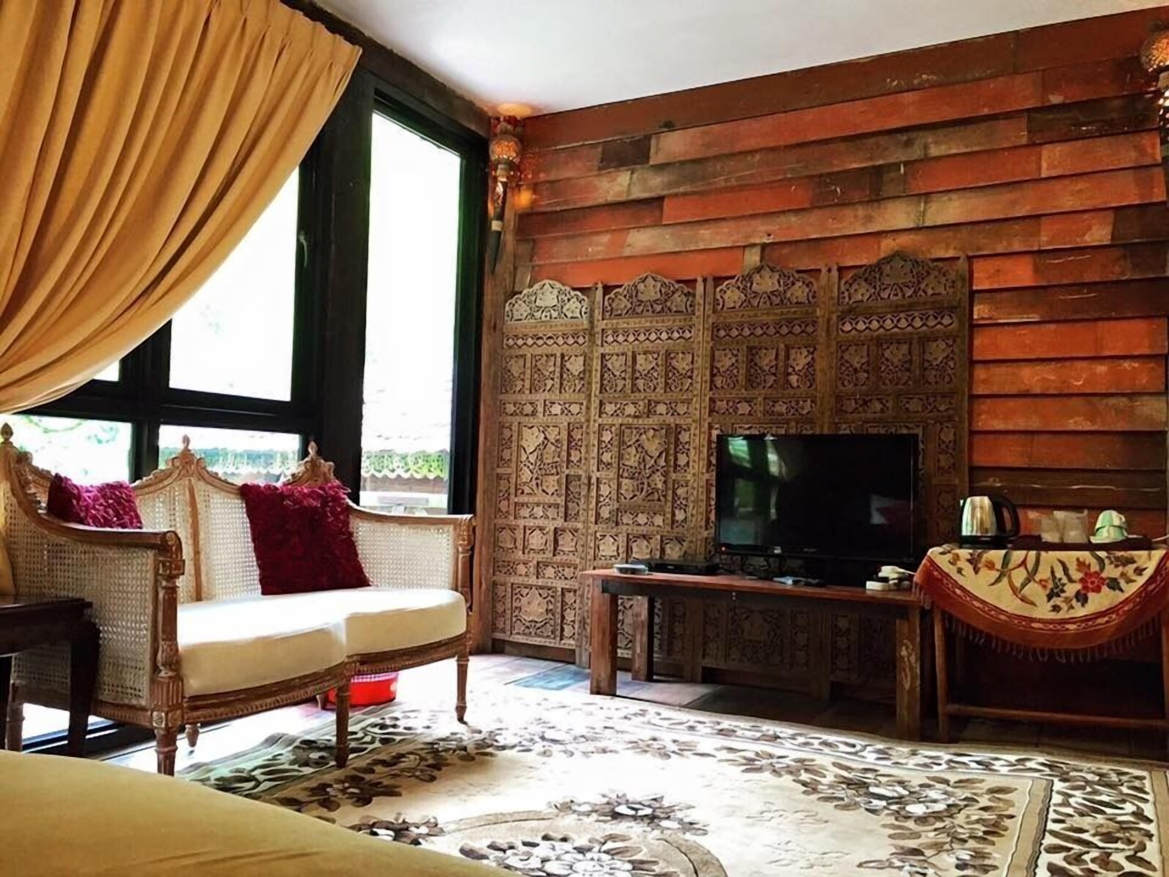 Una habitación con panel de madera, televisor y sofá con un cojín rojo.