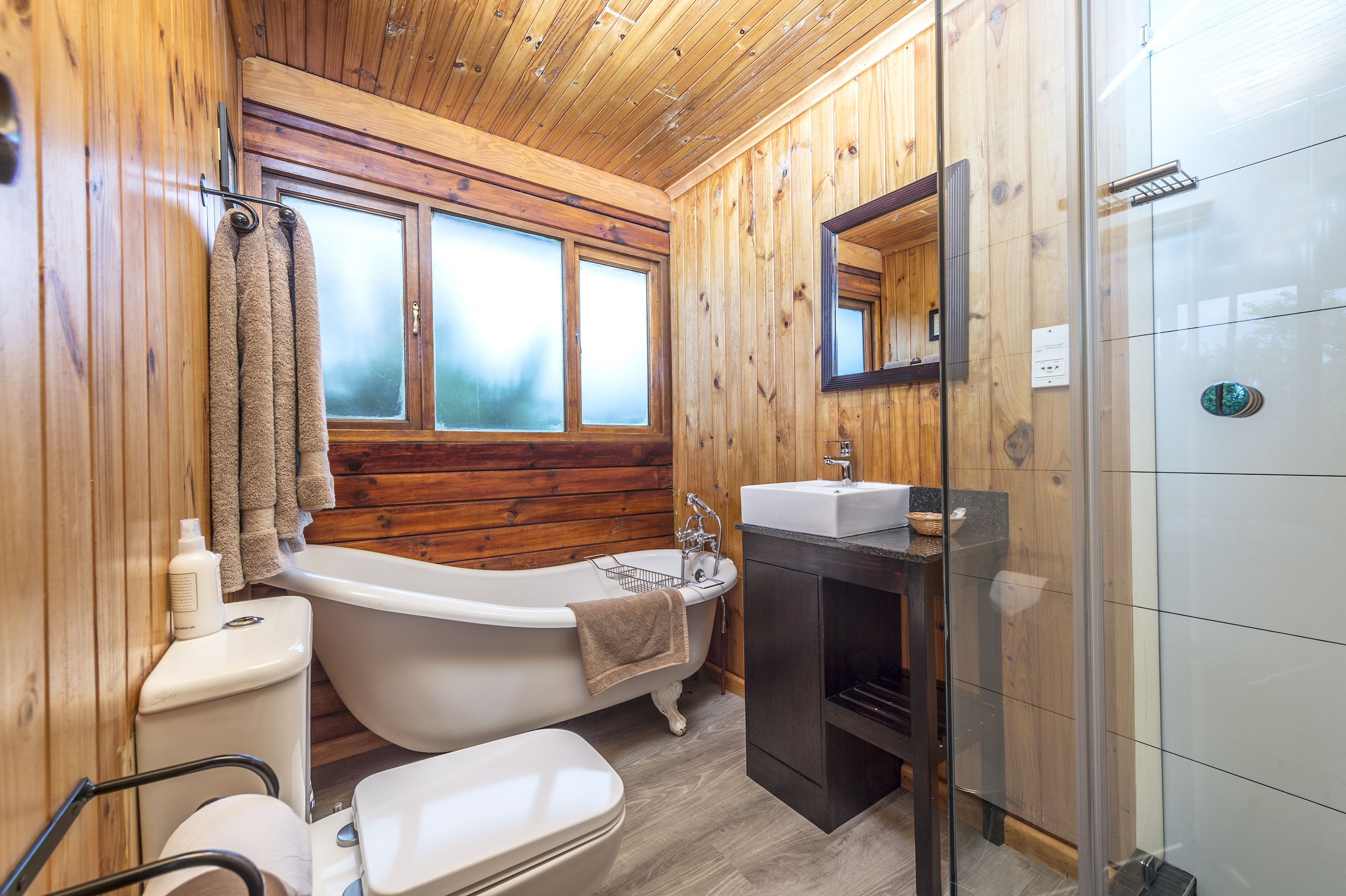 Un baño con paneles de madera, bañera, inodoro y lavabo.