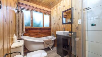 Un baño con paneles de madera, bañera, inodoro y lavabo.