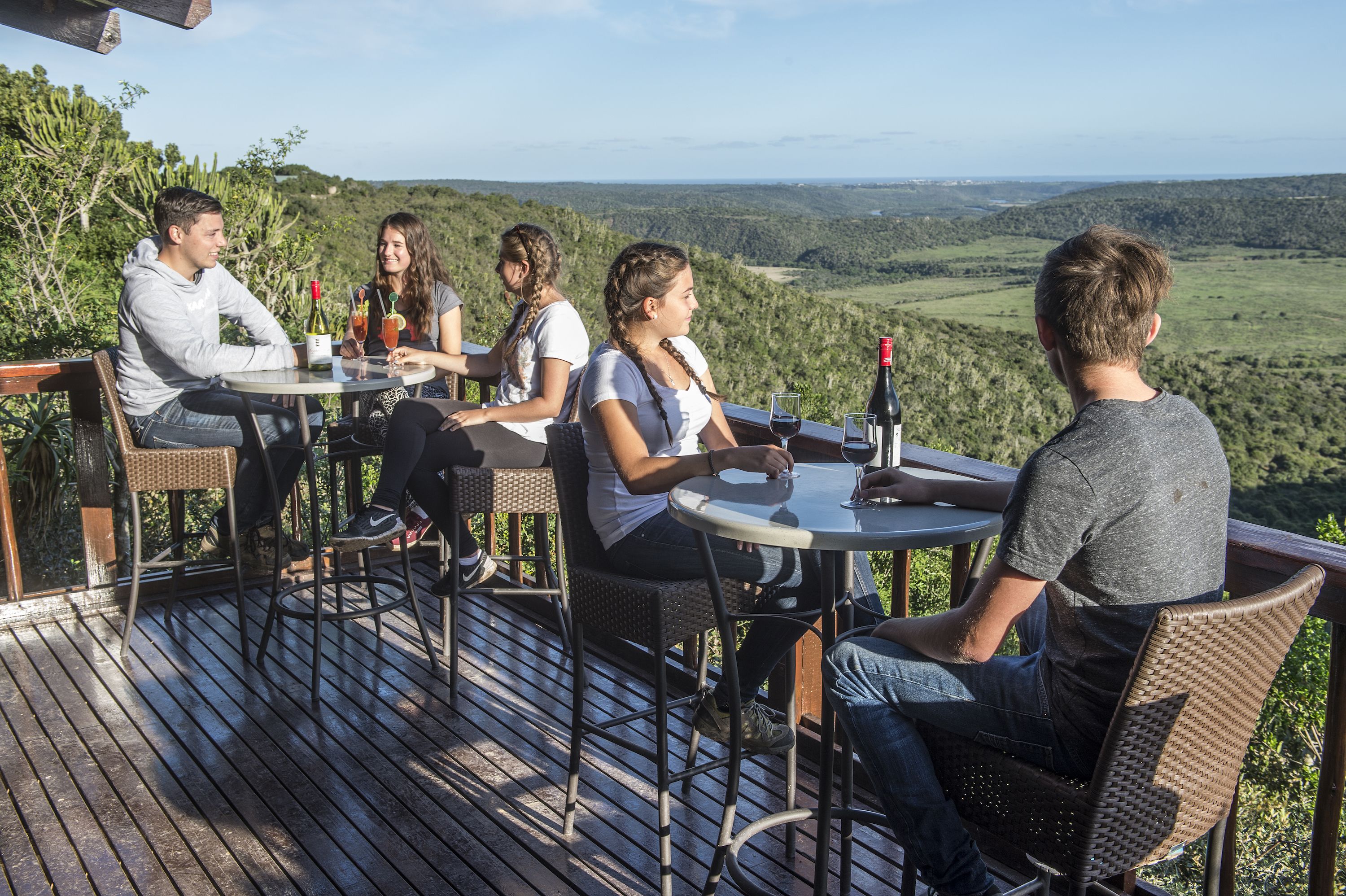 A group of people seated at a table on an outdoor deck with a scenic view.