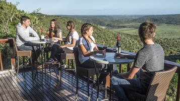 A group of people seated at a table on an outdoor deck with a scenic view.