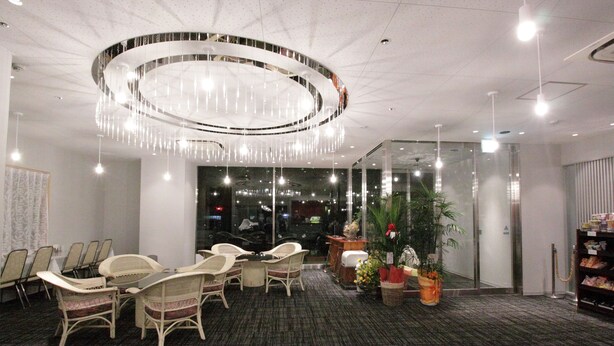 Une salle de conférence dotée d’un lustre moderne, de chaises en osier blanc, d’un sol recouvert de moquette et d’une cloison en verre.
