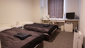 Une chambre d’hôtel avec deux lits, un bureau avec un ordinateur, une chaise, un miroir et une fenêtre avec des rideaux.
