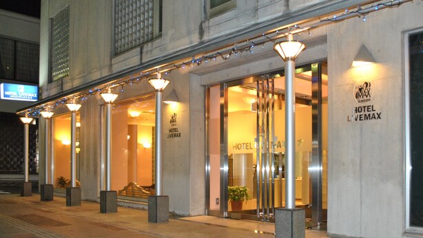 A hotel entrance with a modern design, featuring a glass facade and a sign indicating it is part of the LiveMax Group. - Hotel Live Max Yumoto (Iwaki)