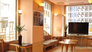 A hotel lobby with seating areas, a television, and a large window with Japanese text. - Hotel Live Max Yumoto (Iwaki)