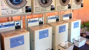 A row of front-loading washing machines with control panels and labels, likely in a laundromat setting. - Hotel Live Max Yumoto (Iwaki)