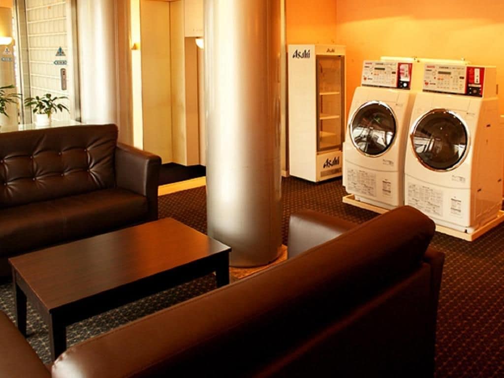 A hotel room with a sofa, a coffee table, and a washing machine.