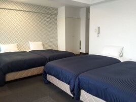 Habitación de hotel con dos camas, cabecera estampada y puerta que da a otra habitación.