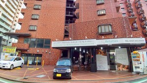A building with a red brick facade, multiple windows, and a sign for 'Relaxation Treatment'. - Hotel Livemax Budget Fuchu (Fuchu)