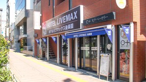 A hotel named HOTEL LIVEMAX with a signboard, a visible entrance, and a storefront with a bakery advertisement. - HOTEL LiVEMAX Korakuen (Tokyo)