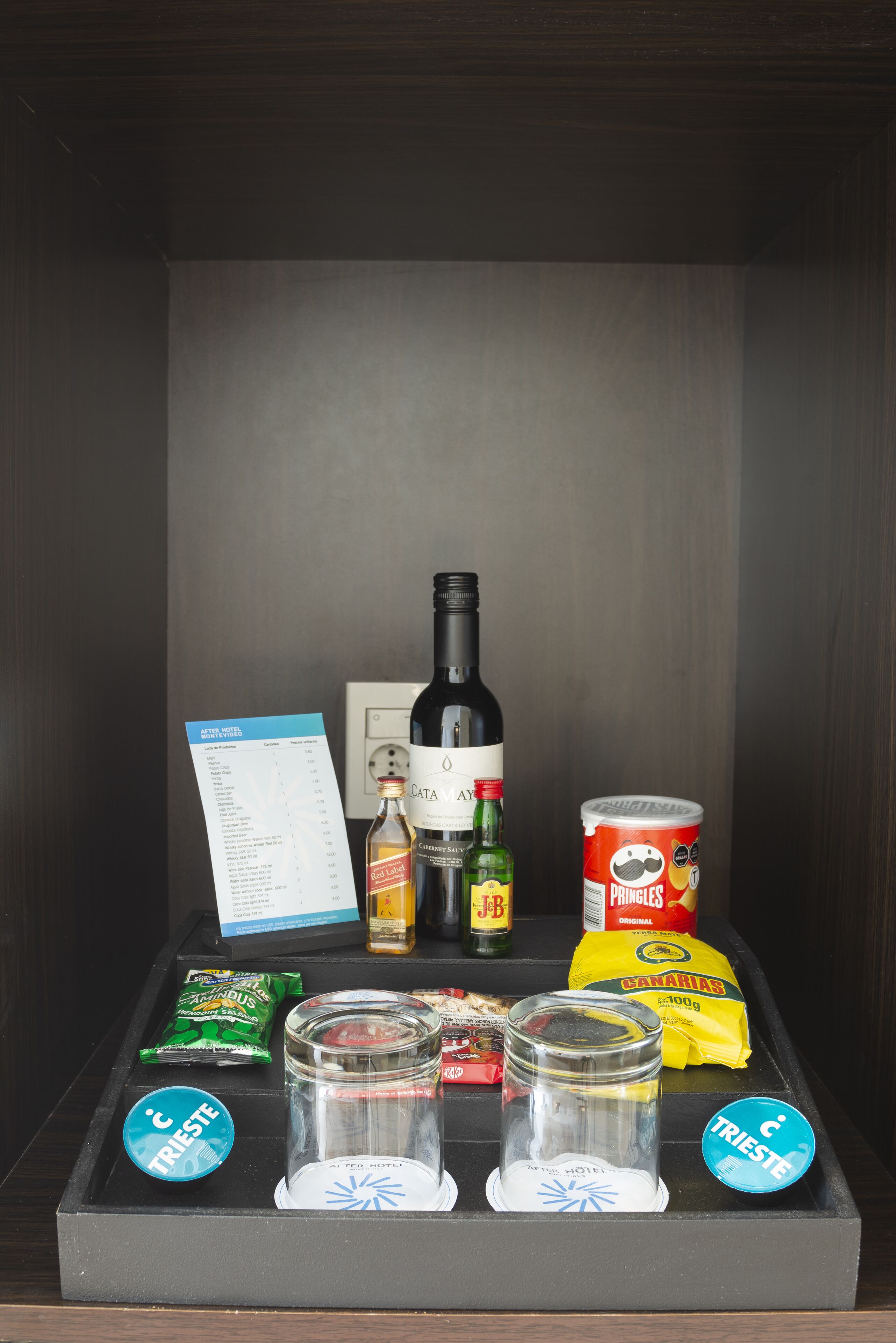 Un minibar con una botella de vino, aperitivos y aderezos.
