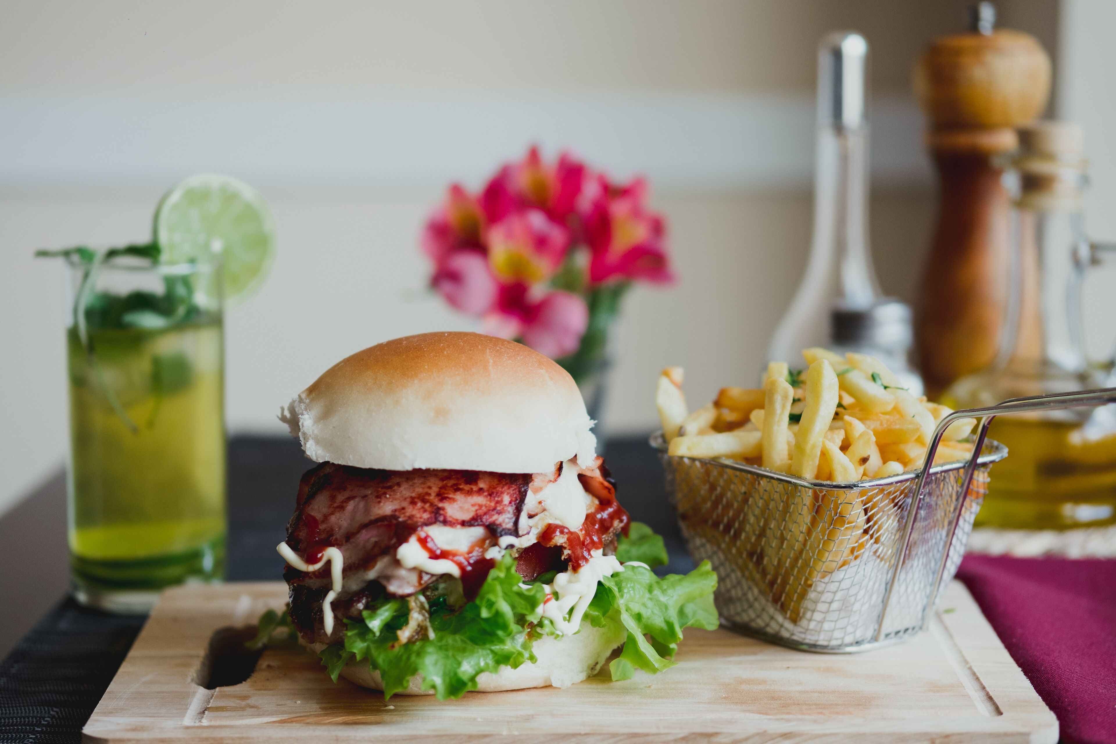 Una hamburguesa con papas fritas y un refresco sobre una tabla de madera.