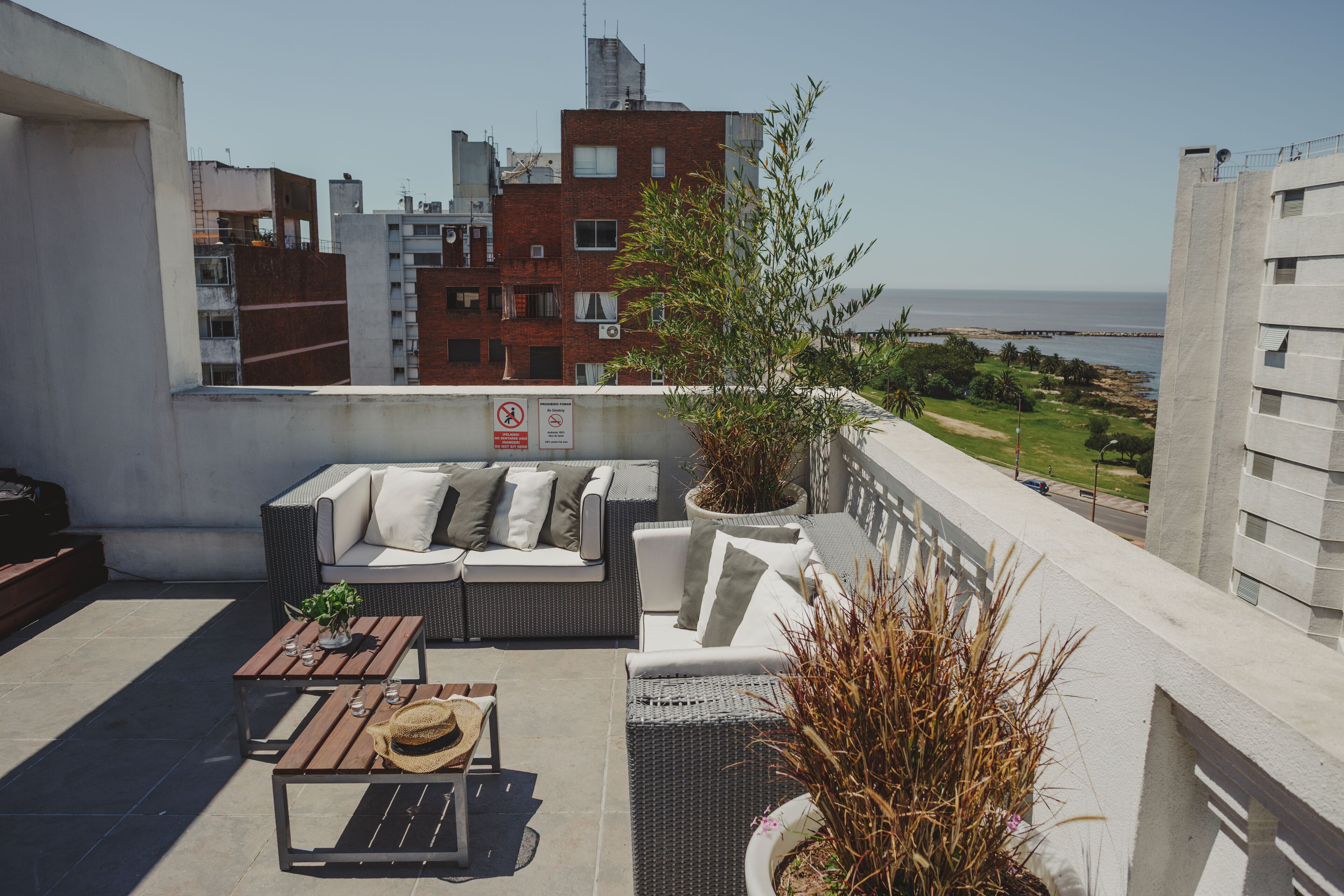 A rooftop terrace with outdoor furniture, a view of the city, and a plant.