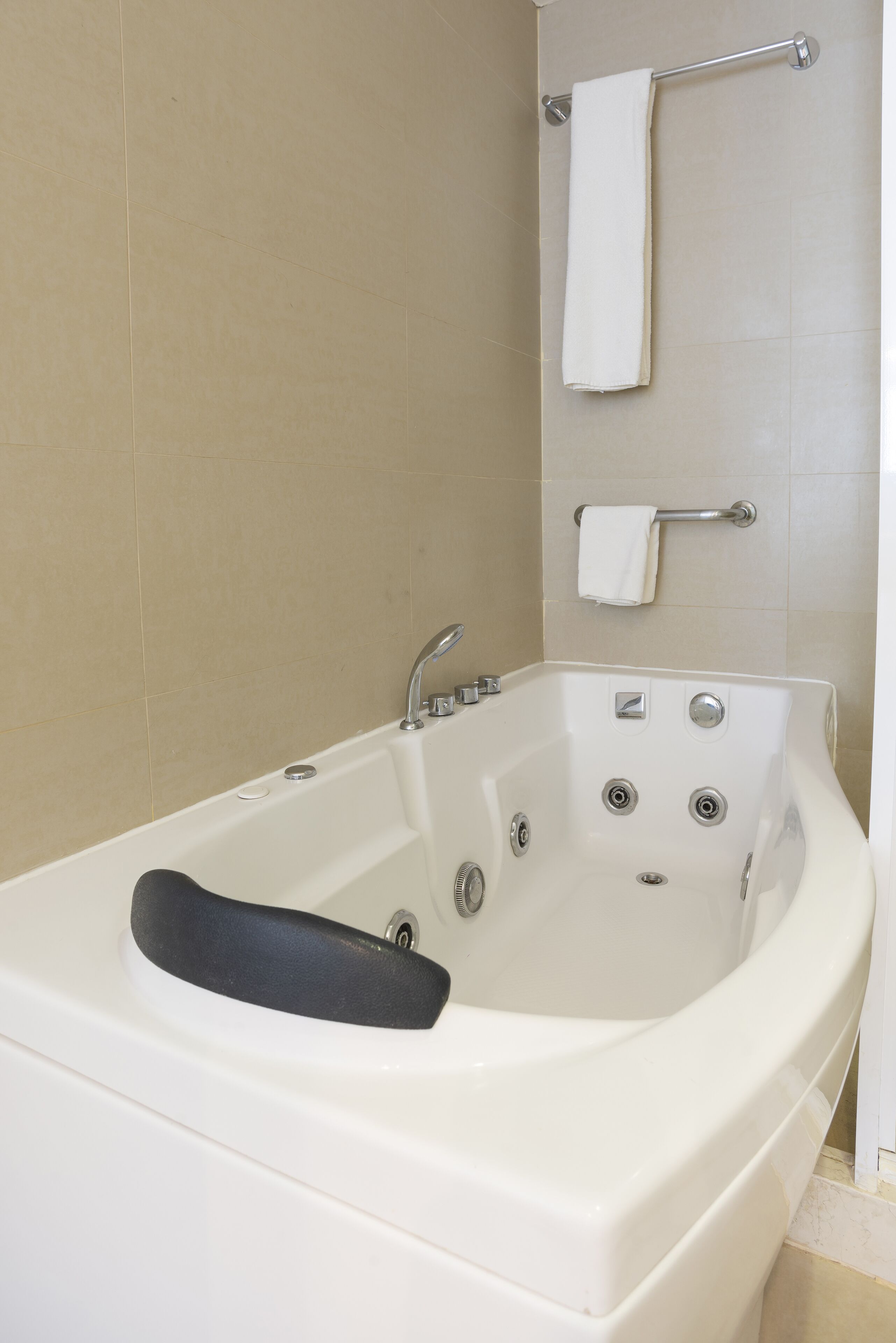 A white bathtub with a black seat, a chrome faucet, and a handheld showerhead.