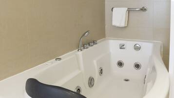 A white bathtub with a black seat, a chrome faucet, and a handheld showerhead.
