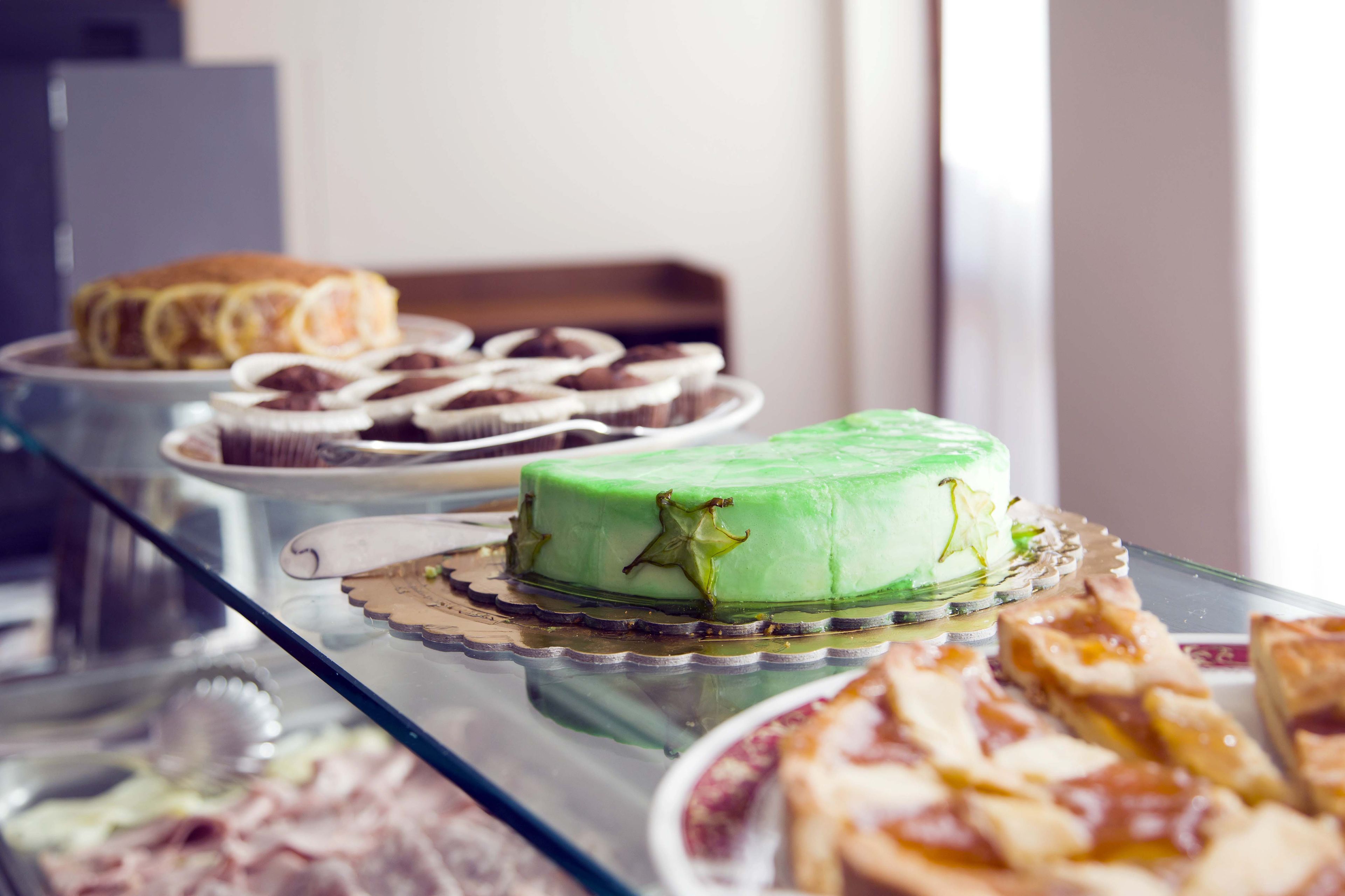 A buffet with various desserts including a green cake, pastries, and pizza slices.