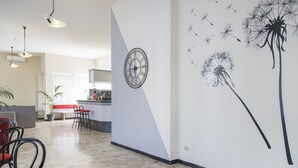 Un salón amplio con cocina, un comedor con sillas rojas y una pared con un reloj y una obra de arte de diente de león.