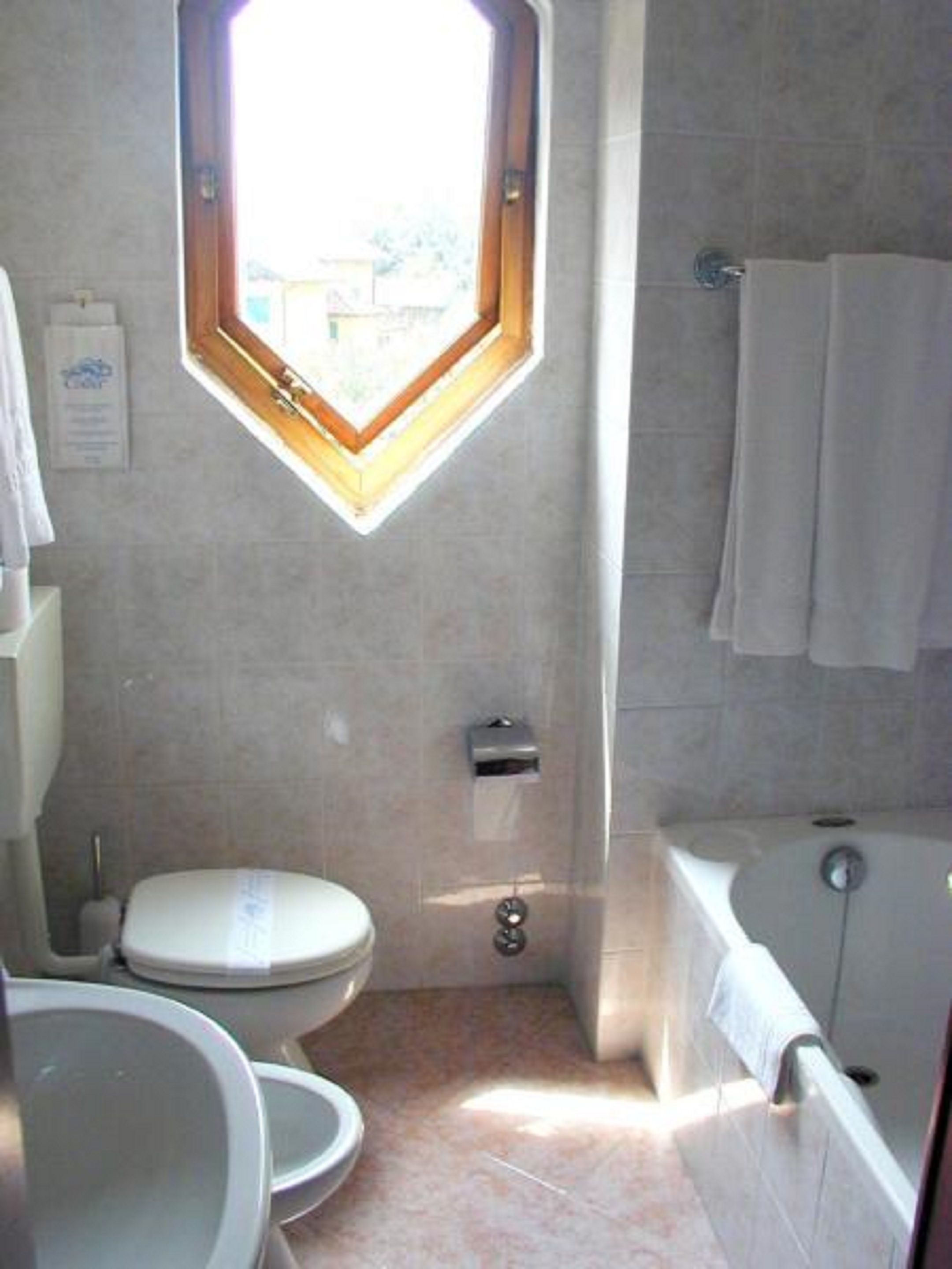 Une salle de bain avec un puits de lumière, des toilettes, une baignoire et un porte-serviettes.