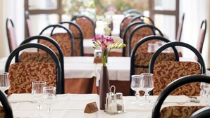 Una mesa de comedor con sillas, un florero con flores y saleros y pimenteros.