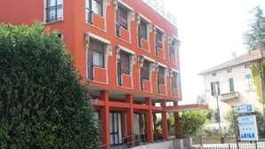 Un edificio rojo con múltiples ventanas y balcones, indicado como hotel.