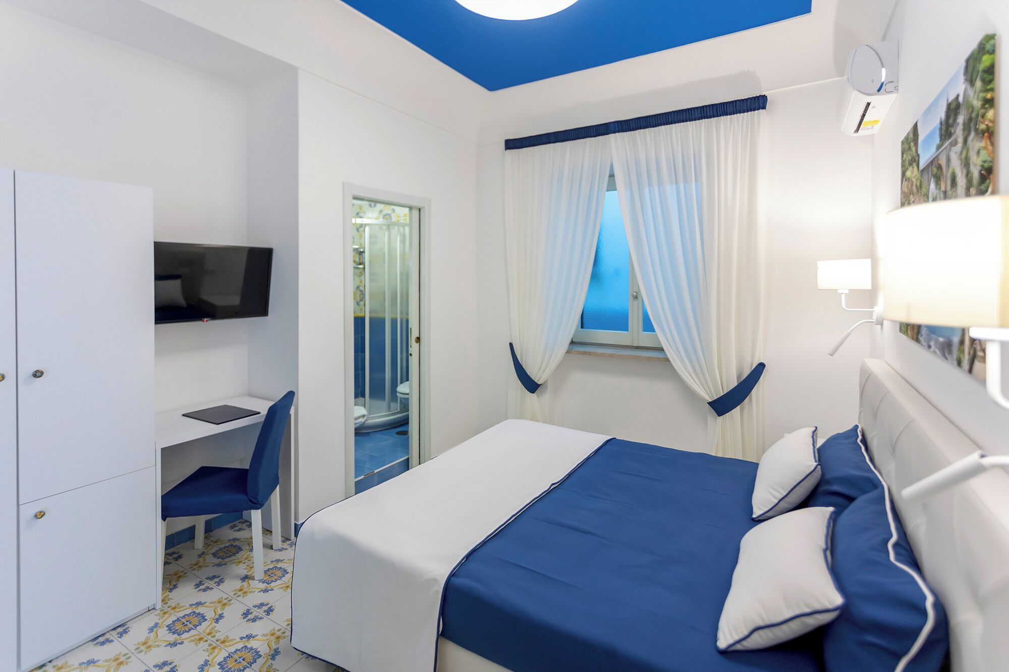 Un dormitorio con cama, escritorio, silla y televisor.