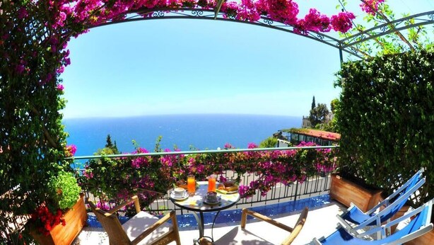 Una terraza con sillas de mimbre y una mesa, con vista al mar.