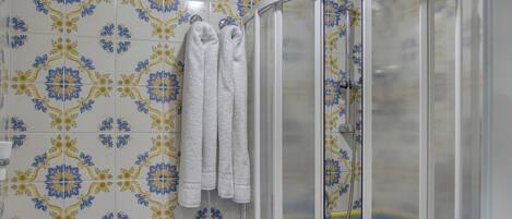 Ein Badezimmer mit Duschkabine, Waschbecken und Fliesen mit Muster.