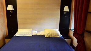 Ein Hotelzimmer mit einem großen Bett, zwei Nachttischen mit Lampen und einem roten Vorhang.