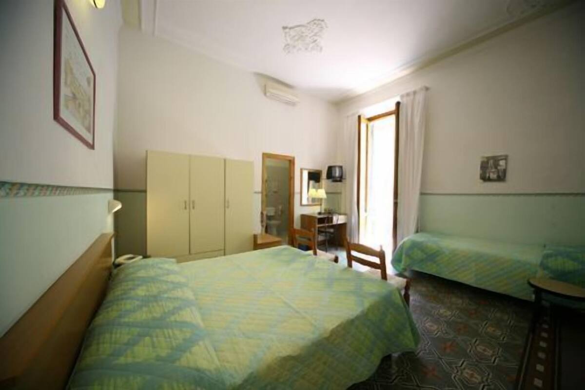 A room with two beds, a wardrobe, a desk, and a mirror.