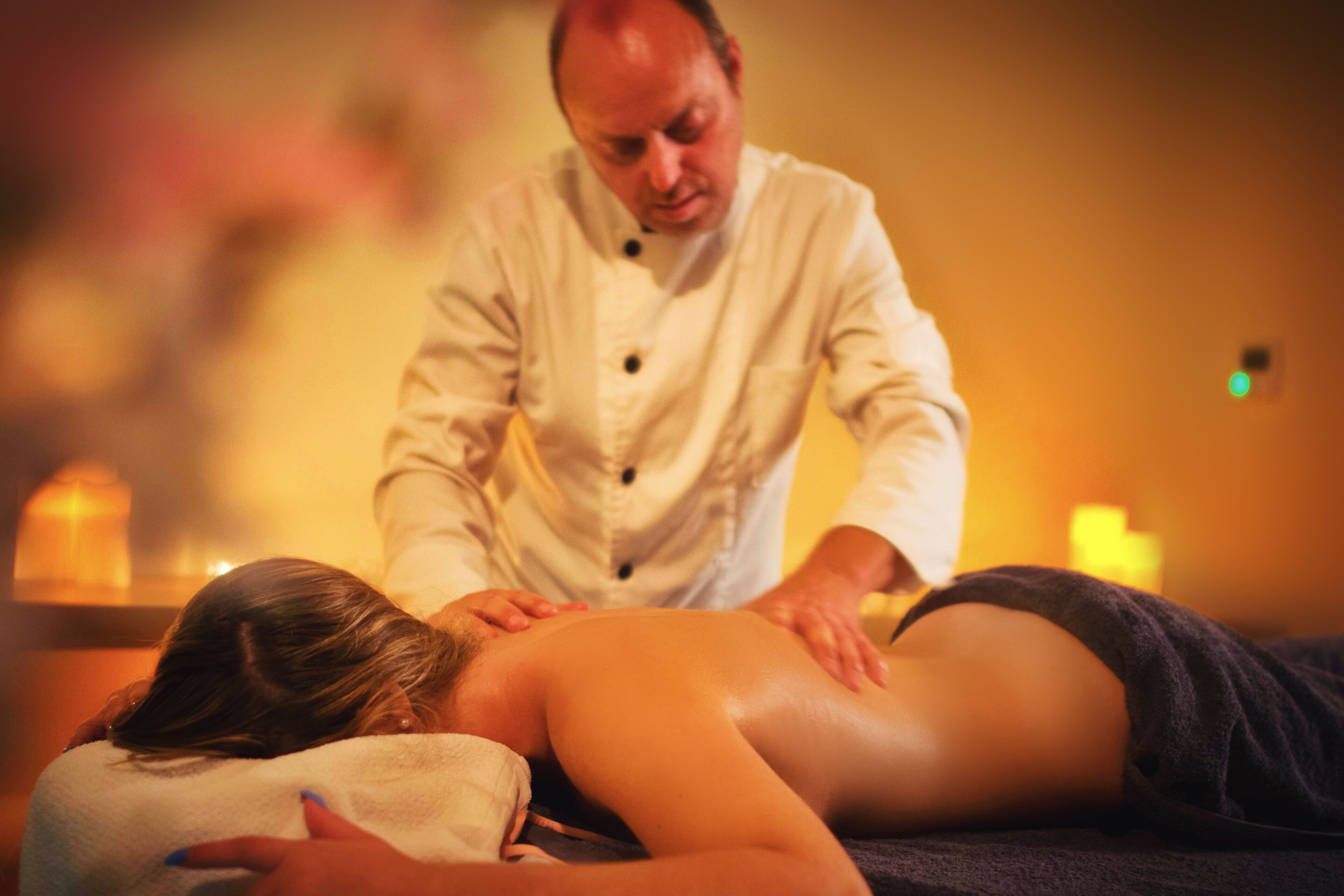 A massage therapy session in a dimly lit room with candles.