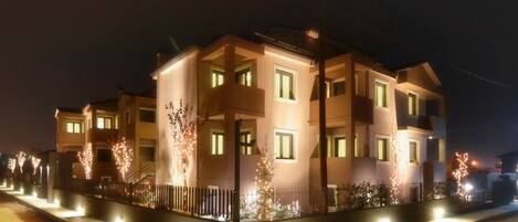 A multi-story residential building with illuminated windows and a well-lit entrance.