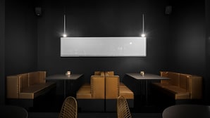 A modern interior with a long table and two booths, a large illuminated screen, and pendant lighting. - Ellopia Point Hotel (Ioannina)
