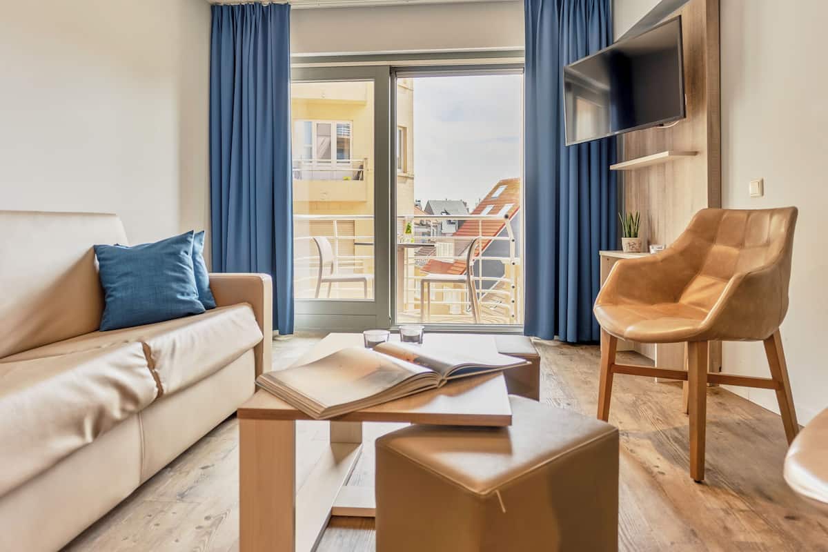 Una sala de estar moderna con un sofá, una mesa de centro, un sillón de cuero y un televisor montado en la pared.