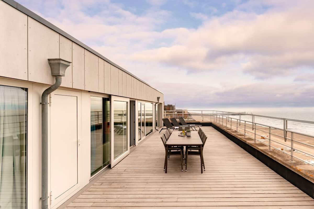 Una terraza con mesa y sillas que da al mar.