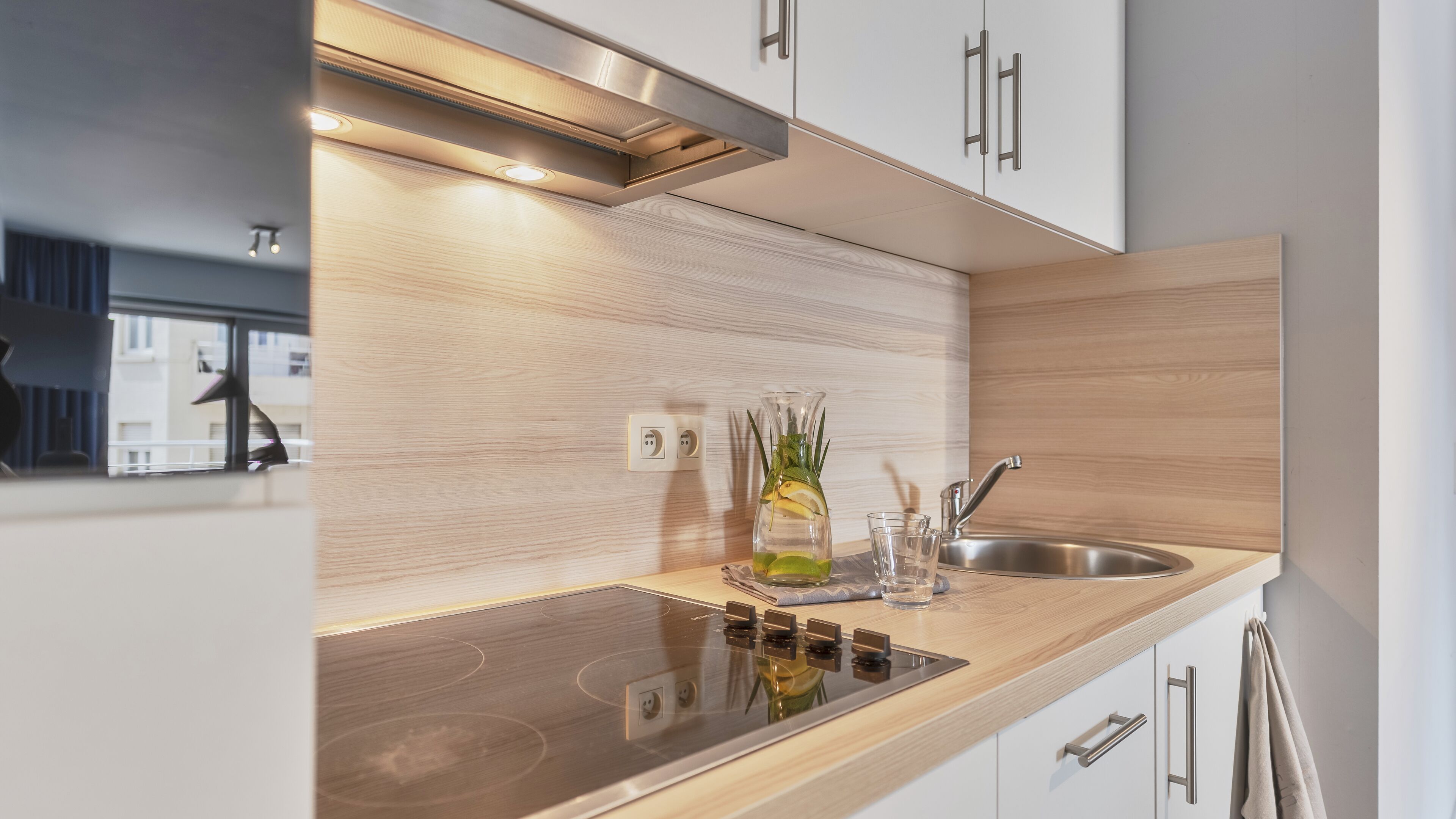 Una cocina moderna con un lavamanos de acero inoxidable, horno empotrado y encimera de madera.
