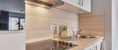 Una cocina moderna con un lavamanos de acero inoxidable, horno empotrado y encimera de madera.
