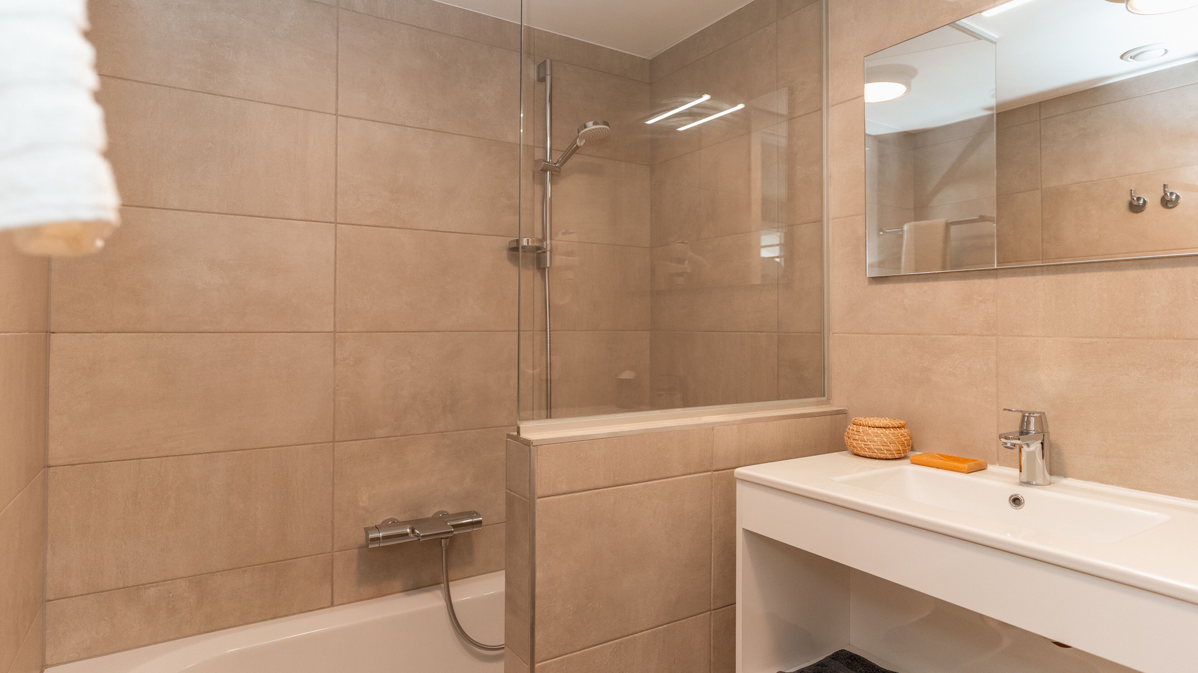 A modern bathroom with a glass-enclosed shower, a white sink, and a mirror above it.
