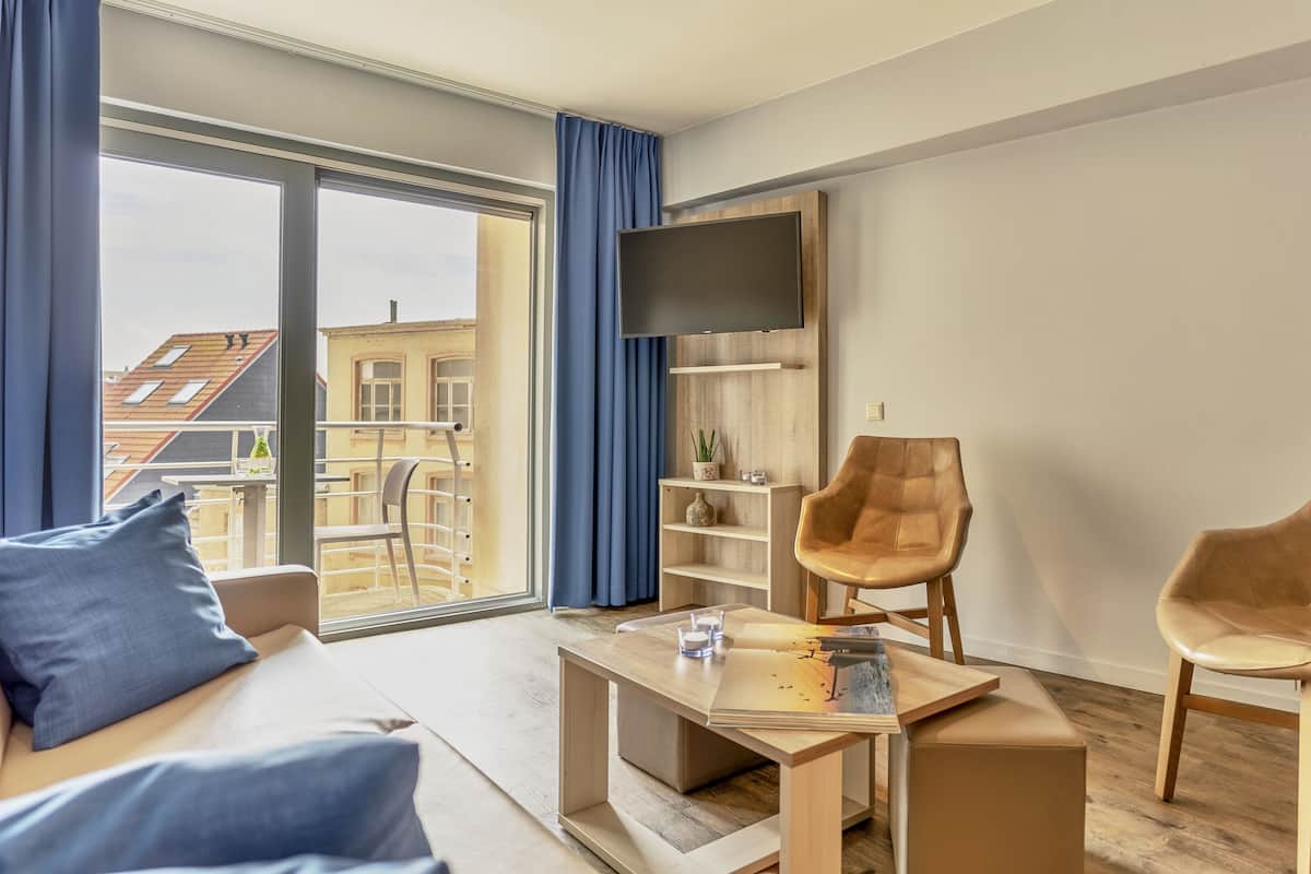 Una sala de estar moderna con un sofá, dos sillones, una mesa de centro y un televisor montado en la pared.