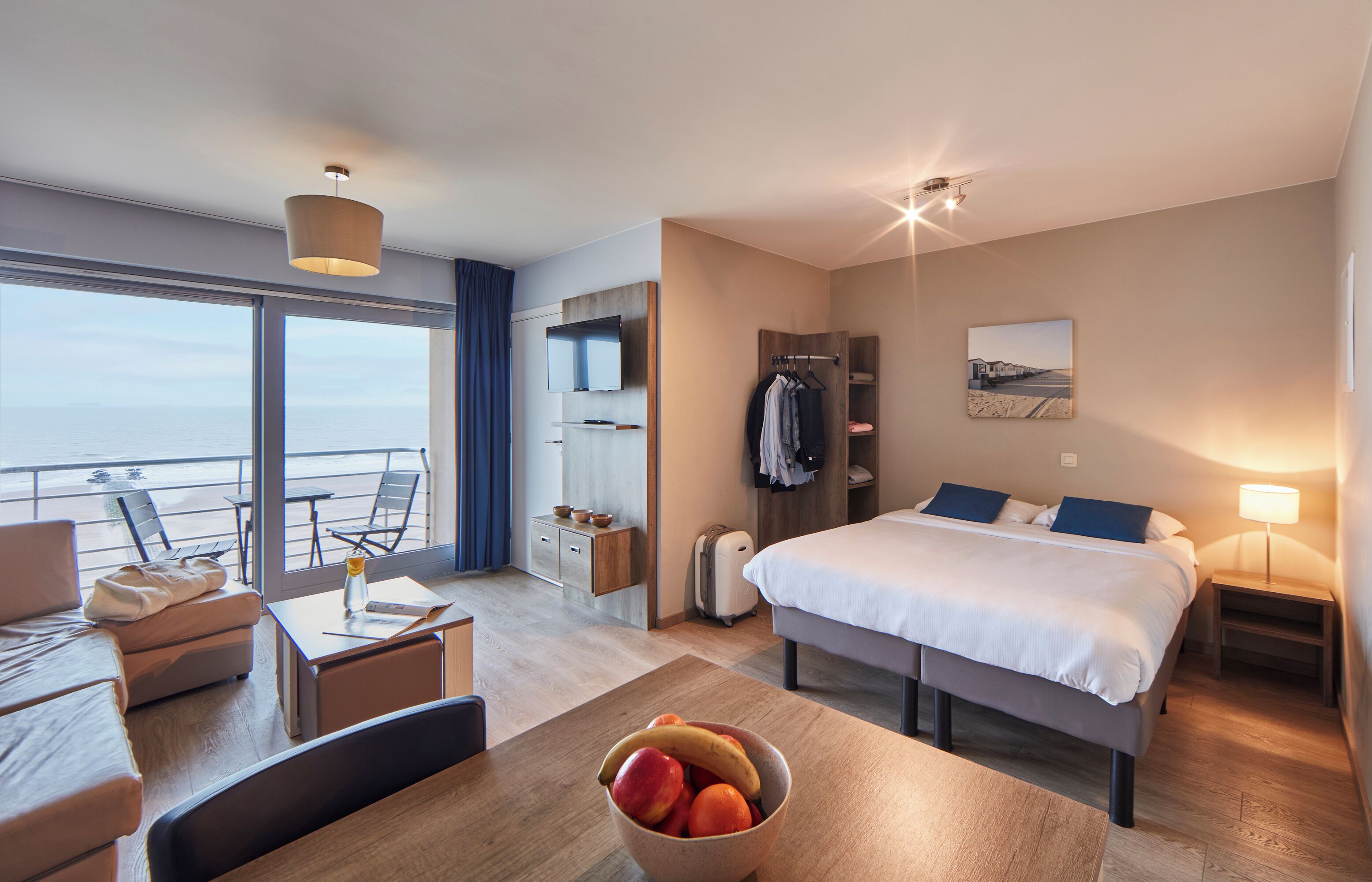 Une chambre d’hôtel comprenant un lit, un bureau, un coin repas, un balcon avec vue et un porte-manteau.