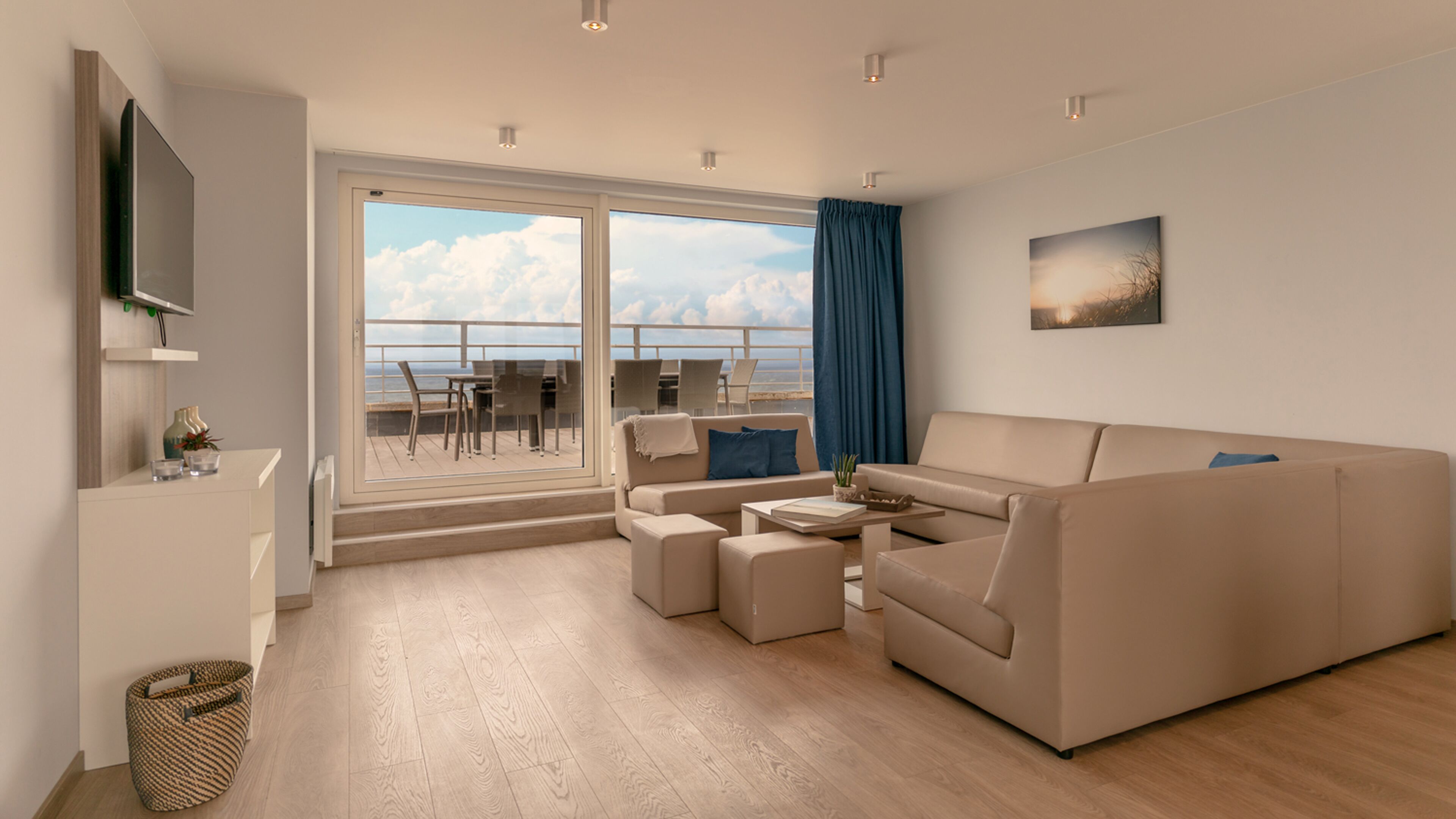 Una sala de estar moderna con sofá, mesa de centro y un balcón con vistas al cielo y nubes.