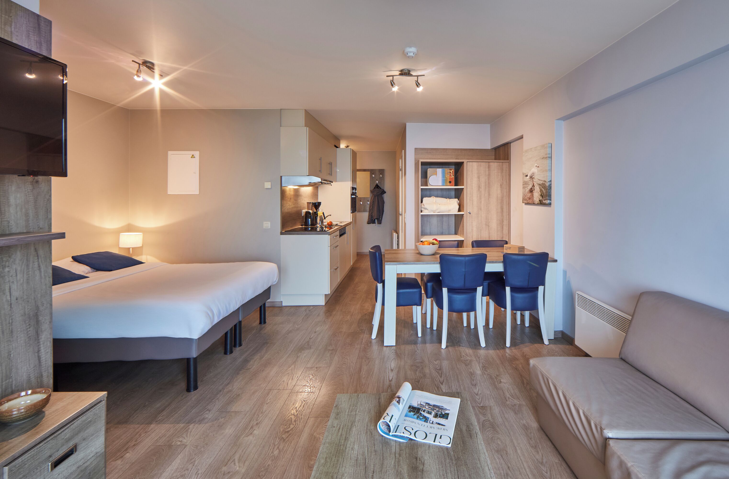 Una habitación de hotel moderna con dos camas, un comedor y una kitchenette.