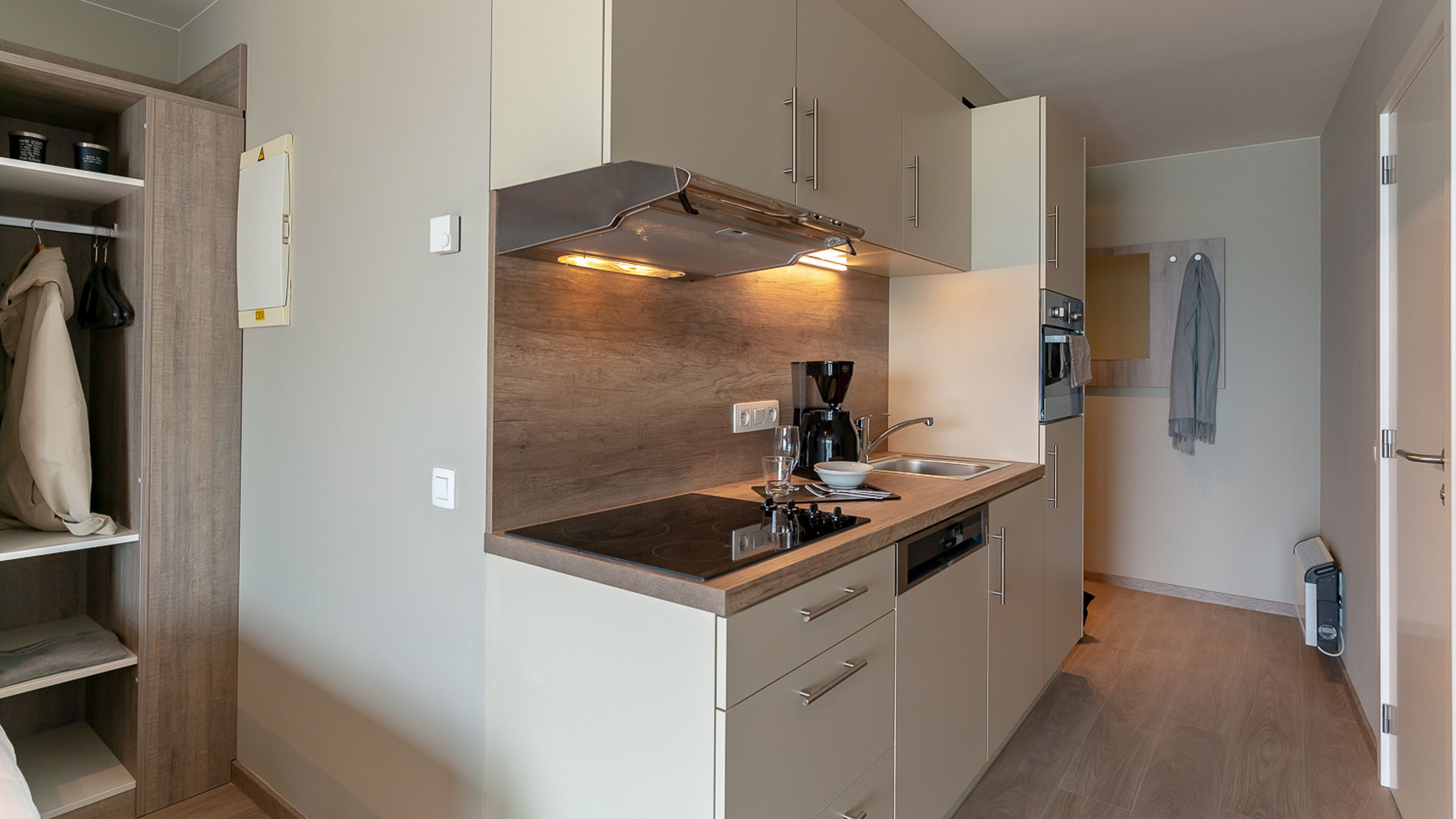 Une cuisine compacte équipée d’une cuisinière intégrée, d’une machine à café et d’un évier.
