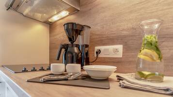 Una cocina moderna con cafetera, jarra de vidrio con limones y un enchufe en la pared.