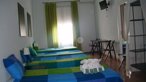 A hotel room with two beds, a desk, a chair, a TV, and a window with curtains. - Puerta del Sol Rooms (Madrid)