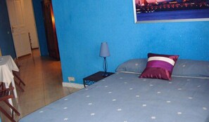 A bedroom with a bed, a nightstand, a lamp, and a view of a cityscape at night. - Puerta del Sol Rooms (Madrid)