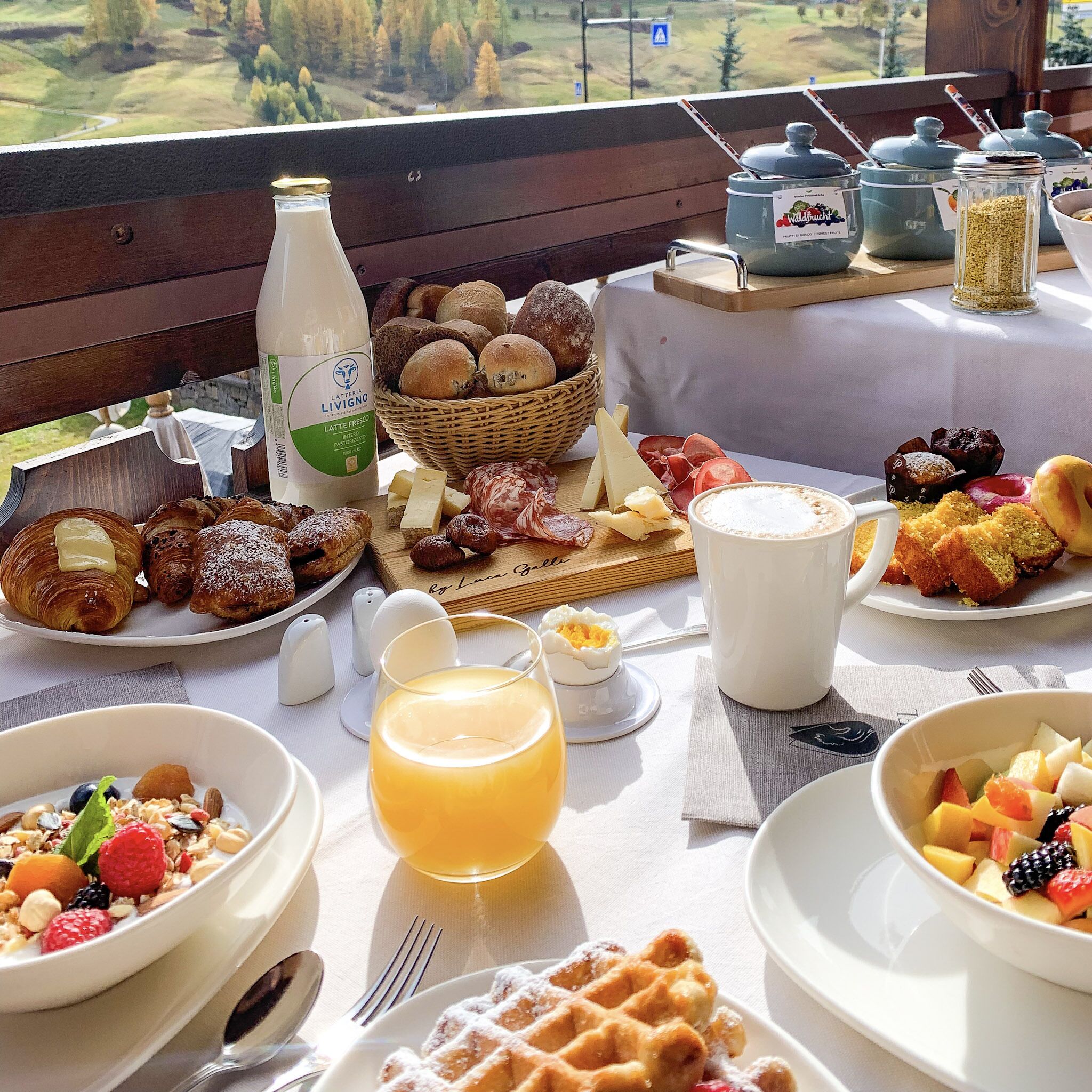 Un buffet de petit-déjeuner proposant une variété de viennoiseries, de fromages et de fruits, le tout disposé sur une table offrant une vue panoramique.