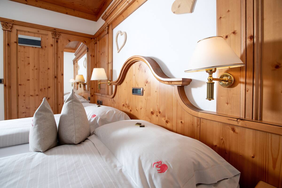 A wooden-paneled room with two beds, each with a pillow and a lamp.